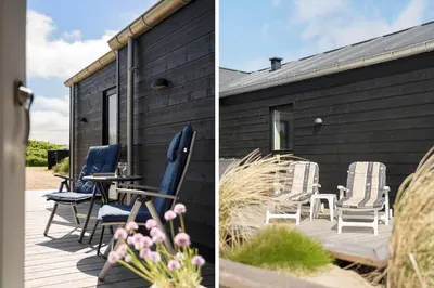 a black house with chairs and a table on a deck at BL1481-Saltum-Kommenvej-1 in Saltum