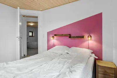 a bedroom with a white bed with a pink wall at BL308-Saltum-Laustvej-24 in Saltum