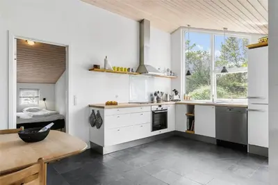 a kitchen with white cabinets and a table and a window at BL747-Saltum-Graabakken-7 in Saltum