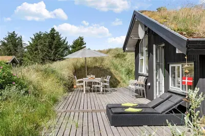 a house with a wooden deck with an umbrella at BL747-Saltum-Graabakken-7 in Saltum