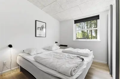a white bedroom with a large bed and a window at BL1110-Blokhus-Bloksbjerg-7 in Blokhus