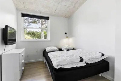 a white bedroom with a bed and a television at BL1110-Blokhus-Bloksbjerg-7 in Blokhus