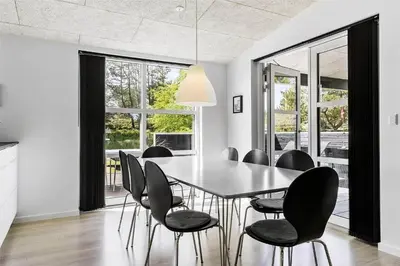 a dining room with a table and black chairs at BL1110-Blokhus-Bloksbjerg-7 in Blokhus
