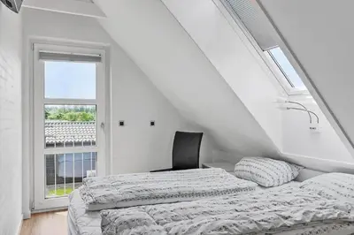 a white bedroom with a bed and a window at BL1509-Blokhus-Stromsvej-7 in Blokhus