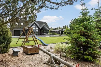 a playground in front of a house with a swing at BL1509-Blokhus-Stromsvej-7 in Blokhus
