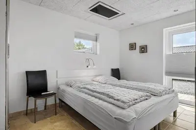 a white bedroom with a bed and a chair at BL1509-Blokhus-Stromsvej-7 in Blokhus