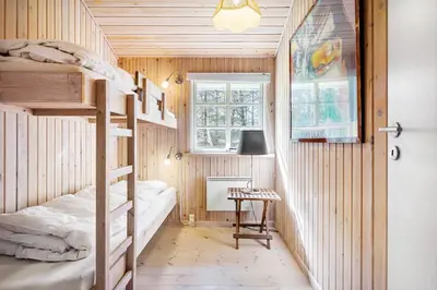 a bunk bed room with two bunk beds and a desk at BL387-Blokhus-Berberisvej-51 in Blokhus