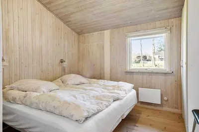 a large bed in a room with a window at BL387-Blokhus-Berberisvej-51 in Blokhus