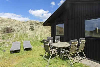 a table and chairs sitting next to a black house at BL808-Pandrup-Hare-hop-5 in Pandrup