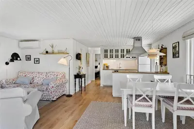 a white living room with a table and a kitchen at BL1408-Pandrup-Hunetorp-Klitvej-243 in Pandrup