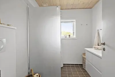 a bathroom with a white refrigerator and a window at BL1398-Pandrup-Rodhus-Klitvej-135 in Pandrup