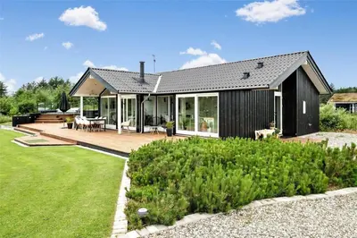 a black house with a deck and a yard at BL425-Saltum-Tippen-22 in Saltum