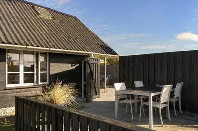 a wooden deck with a table and chairs on a house at BL1498-Blokhus-Bag-Somaerket-22 in Blokhus