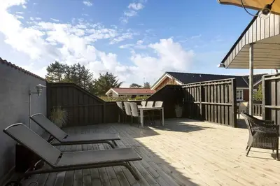 a patio with chairs and a table on a wooden deck at BL1498-Blokhus-Bag-Somaerket-22 in Blokhus