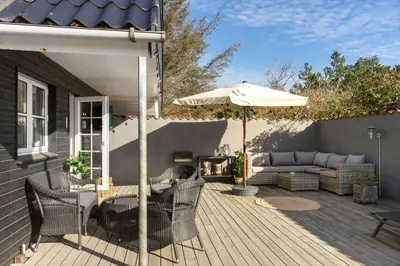 a patio with a couch and an umbrella at BL1498-Blokhus-Bag-Somaerket-22 in Blokhus