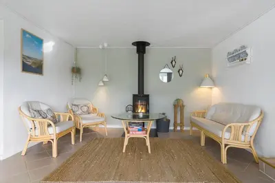 a living room with chairs and a table and a stove at BL1498-Blokhus-Bag-Somaerket-22 in Blokhus