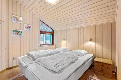 a bedroom with a bed with white sheets and a window at BL160-Blokhus-Bag-Hojen-68 in Blokhus