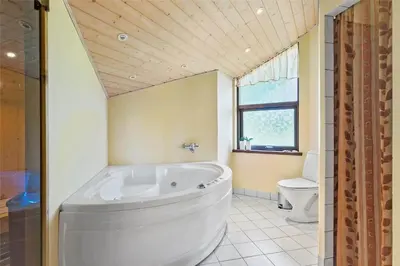a large white tub in a bathroom with a toilet at BL160-Blokhus-Bag-Hojen-68 in Blokhus