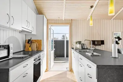 a kitchen with white cabinets and a black counter top at BL826-Saltum-Haresvinget-7 in Saltum