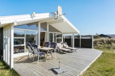 a wooden deck with chairs and a table on it at BL826-Saltum-Haresvinget-7 in Saltum