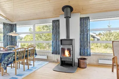 a fireplace in a living room with a table and chairs at BL152-Saltum-Kvansletten-33 in Saltum