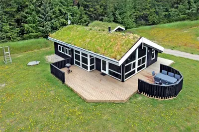 a small house with a grass roof with a deck at BL486-Saltum-Laustvej-32 in Saltum