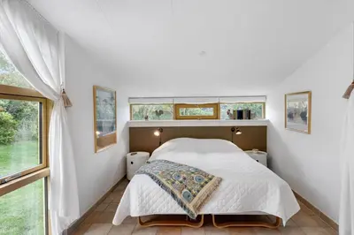 a bedroom with a bed and two windows at BL1318-Blokhus-Vesterhavsbakken-28 in Blokhus