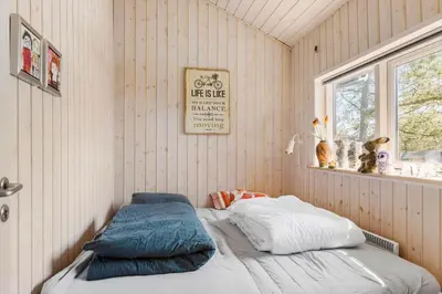 a bedroom with a bed in a room with a window at BL1702-Blokhus-Krylevej-3 in Blokhus