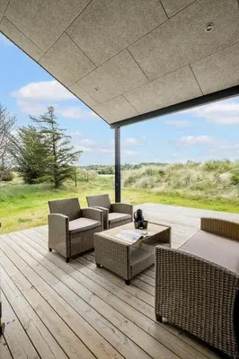 a patio with wicker chairs and tables on a wooden deck at BL1411-Blokhus-Ribergaardsvej-15 in Blokhus