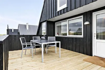 a black house with a table and chairs on a deck at BL1193-Pandrup-Narhvalen-14 in Pandrup