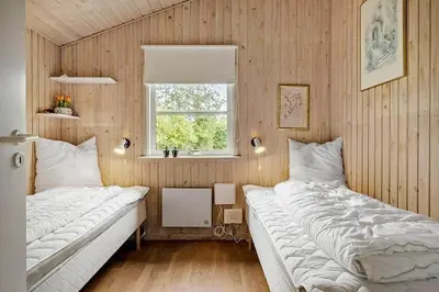 a bedroom with two beds and a window at BL1345-Blokhus-Berberisvej-59 in Blokhus