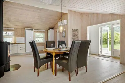 a dining room with a wooden table and black chairs at BL1345-Blokhus-Berberisvej-59 in Blokhus