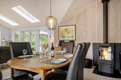 a dining room with a table and a fireplace at BL1345-Blokhus-Berberisvej-59 in Blokhus