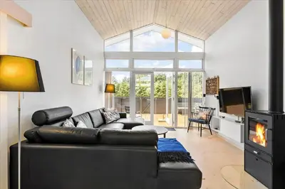 a living room with a leather couch and a fireplace at BL540-Saltum-Trehoje-9 in Saltum