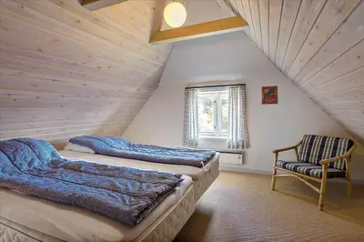 a attic bedroom with two beds and a chair at BL1449-Blokhus-Kienersvej-8 in Blokhus