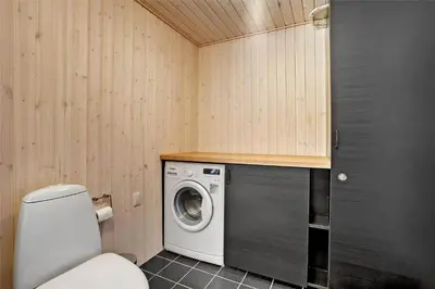 a bathroom with a toilet and a washing machine at BL1066-Pandrup-Rodhus-Skolevej-17 in Pandrup