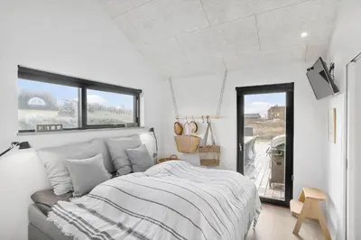 a white bedroom with a bed and a window at BL1427-Blokhus-Ovesensvej-9 in Blokhus