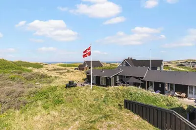 a house on top of a hill with a canadian flag at BL137-Blokhus-Pirupshvarre-Klit-6 in Blokhus