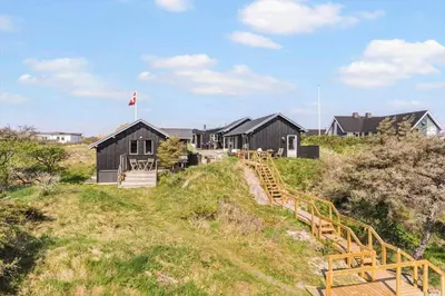 a row of black houses on a hill with a wooden staircase at BL137-Blokhus-Pirupshvarre-Klit-6 in Blokhus