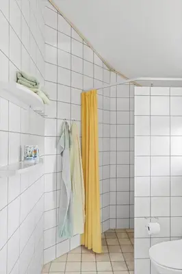 a bathroom with a yellow shower curtain and towels at BL137-Blokhus-Pirupshvarre-Klit-6 in Blokhus