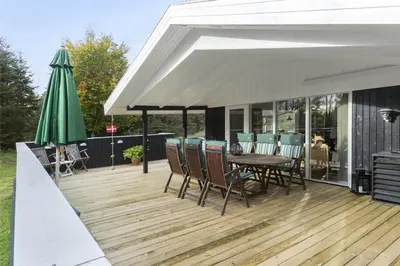 a deck with a table and chairs and an umbrella at BL1379-Blokhus-Saetergaardsvej-8 in Blokhus