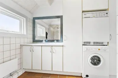 a white bathroom with a washing machine and a sink at BL1169-Blokhus-Berberisvej-5 in Blokhus