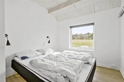 a bed in a white room with a window at BL1169-Blokhus-Berberisvej-5 in Blokhus