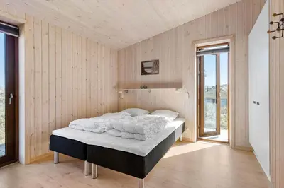 a bedroom with a bed in a room with wooden walls at BL1350-Blokhus-Taarnfalkevej-29 in Blokhus