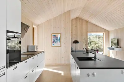 a kitchen with white cabinets and a black counter top at BL1350-Blokhus-Taarnfalkevej-29 in Blokhus