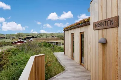 a house with a wooden walkway next to a building at BL1350-Blokhus-Taarnfalkevej-29 in Blokhus