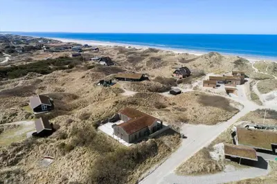 an aerial view of a house on a hill next to the ocean at BL1350-Blokhus-Taarnfalkevej-29 in Blokhus