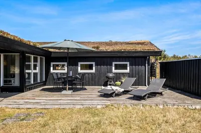 a deck with chairs and an umbrella and a grill at BL112-Saltum-Kvansletten-20 in Saltum