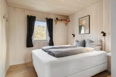 a white bed in a room with a window at BL1502-Blokhus-Graevlingevej-3 in Blokhus