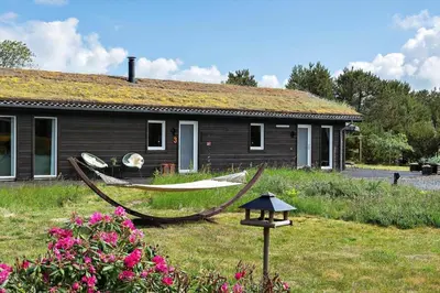 a house with a hammock in front of it at BL1502-Blokhus-Graevlingevej-3 in Blokhus